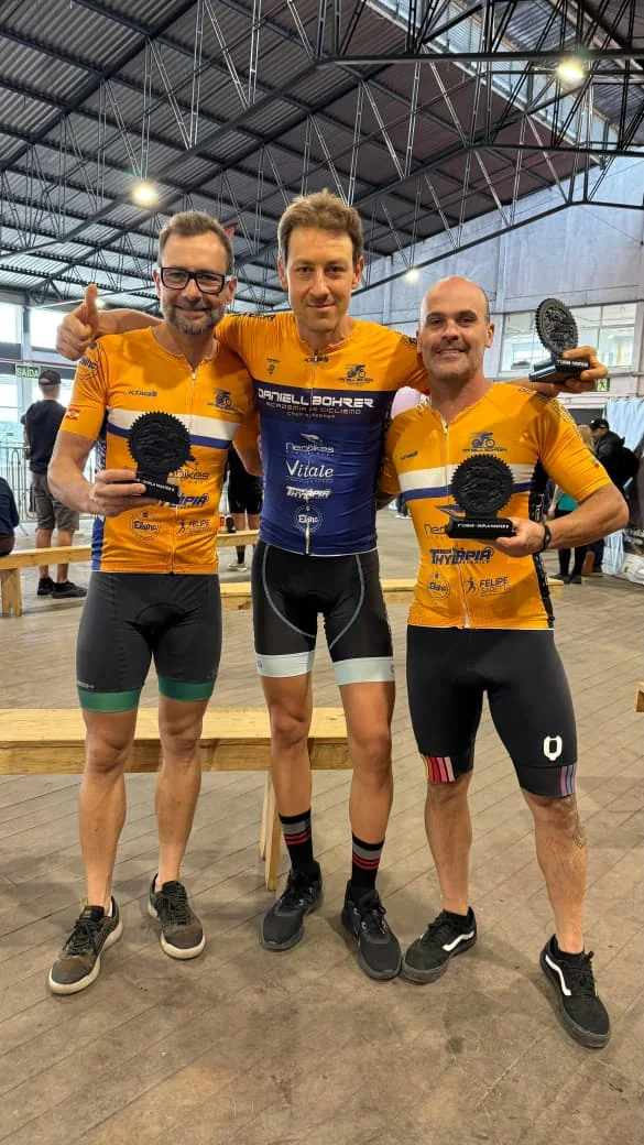 Três ciclistas celebram juntos após uma competição