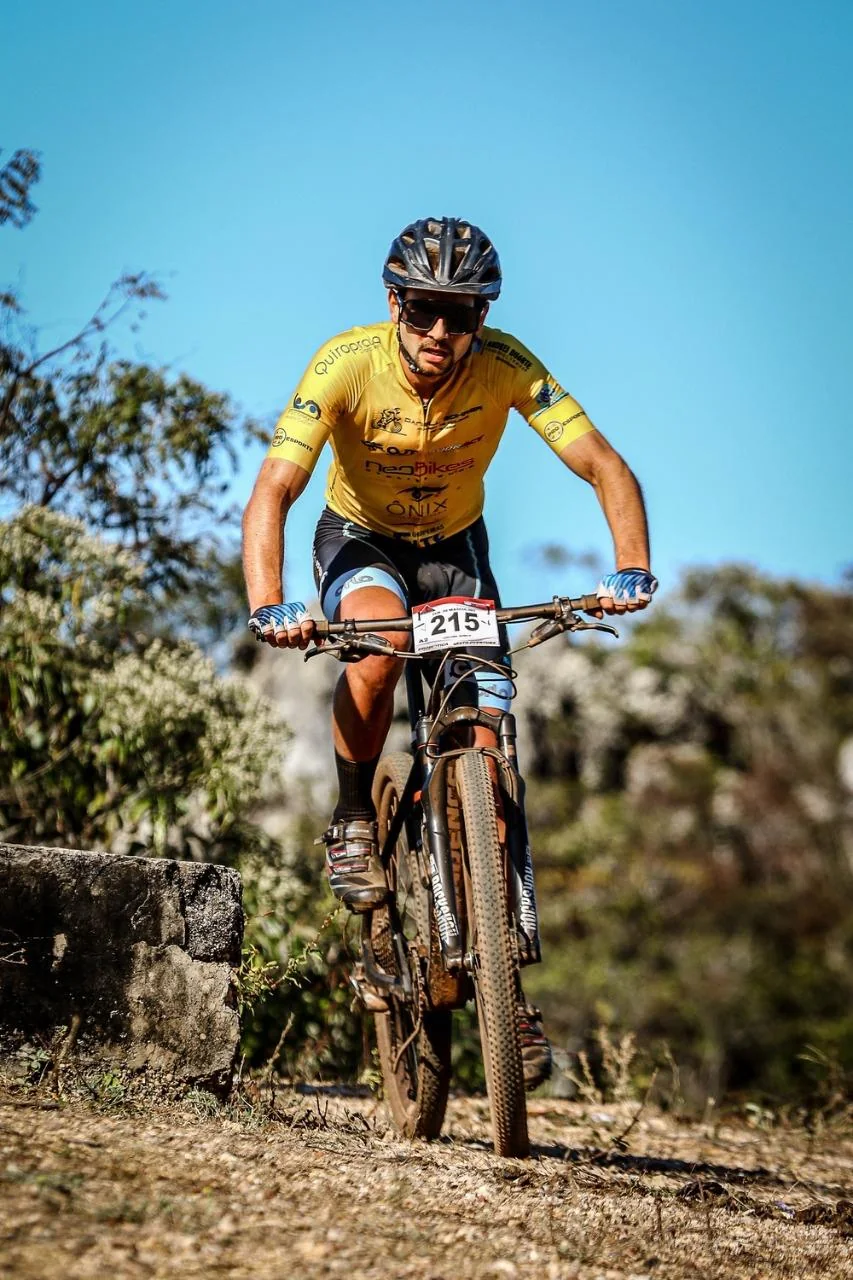 Mountain biker de uniforme amarelo avança por uma trilha